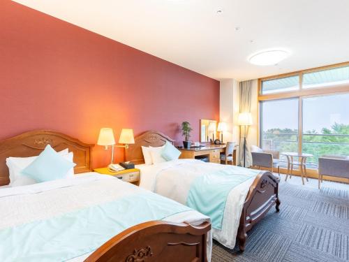 a hotel room with two beds and a large window at LiVEMAX Resort Upopoi Shiraoi Onsen in Shiraoi