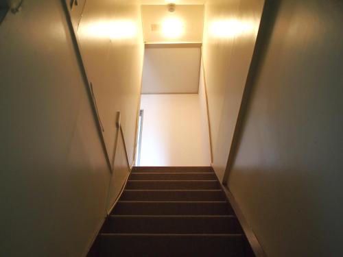 a hallway with stairs with a light at the top at ゲストハウスサンパティオ in Shingu