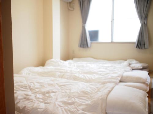 an unmade bed in a room with a window at ゲストハウスサンパティオ in Shingu