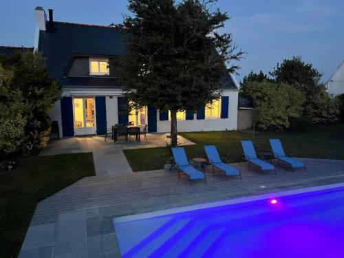 un groupe de chaises bleues assises devant une maison dans l'établissement Belle Villa, piscine chauffée et proche plages, à Erdeven