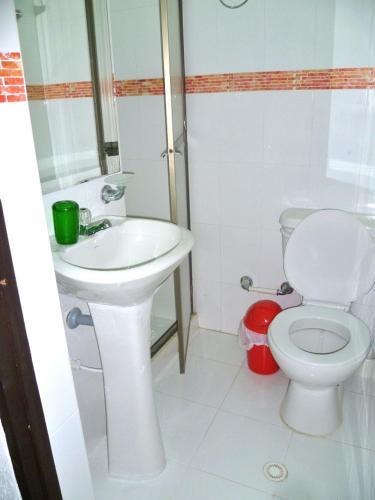 a white bathroom with a toilet and a sink at Casa Los Almendros in Melgar