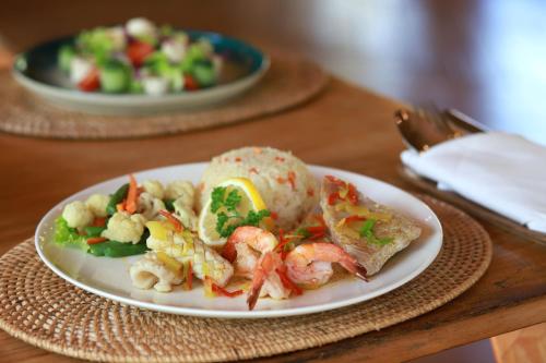 Bila Penida Resort & Farm في نوسا بينيدا: طبق من الطعام مع الجمبري والخضار على الطاولة