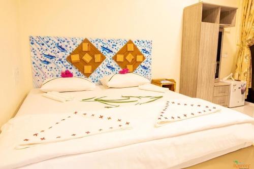 a white bed with two pillows on top of it at Summer Vibes Beach Front in Rasdu