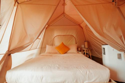 a bed in a canvas tent with an orange pillow at Campgrounds at Mantalongon in Dalaguete