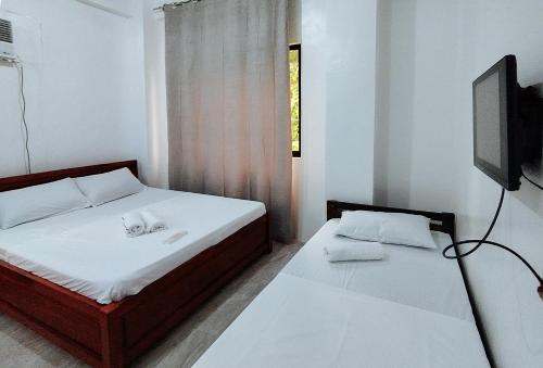 a bedroom with two beds and a tv on the wall at RedDoorz at Elton Guesthouse in Numancia