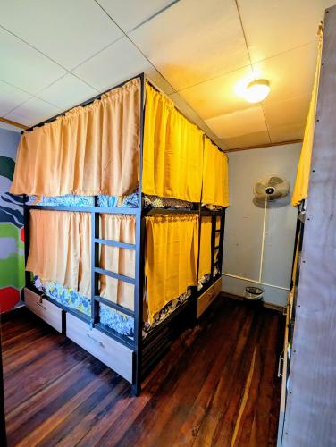 a room with two bunk beds with yellow curtains at Mangifera Hostel in Grecia