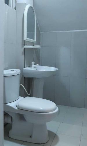 a white bathroom with a toilet and a sink at Lilly Rooms in Kandy