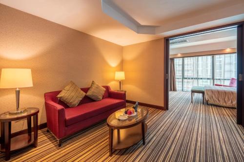 a hotel room with a red couch and a bed at Leeden Hotel Guangzhou in Guangzhou