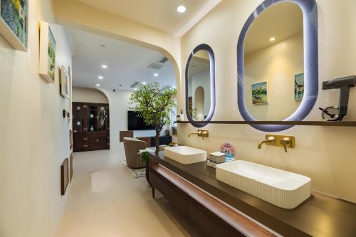 a bathroom with two sinks and two mirrors at Guangzhou He She Art Apartment in Guangzhou