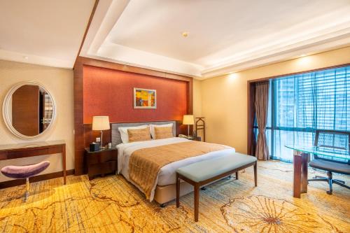 a bedroom with a bed and a desk and a window at Leeden Hotel Guangzhou in Guangzhou