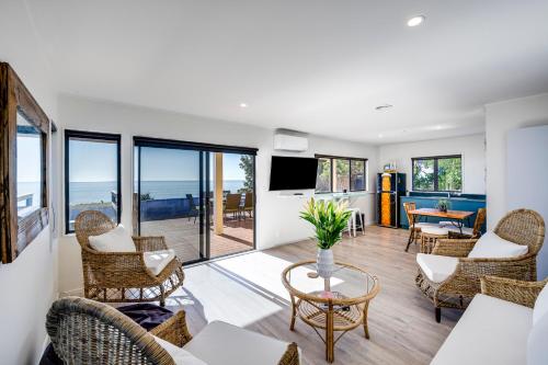 a living room with chairs and a couch and a table at Coastal Embrace - Te Awanga Seaview Escape in Te Awanga