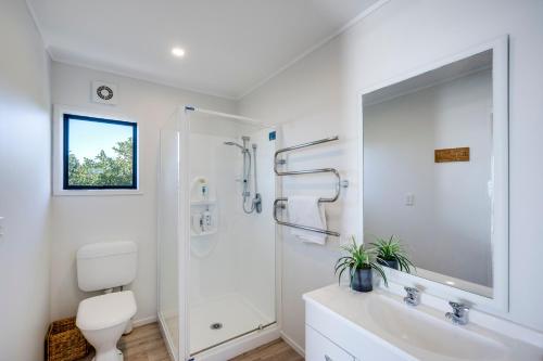 a white bathroom with a toilet and a shower at Coastal Embrace - Te Awanga Seaview Escape in Te Awanga