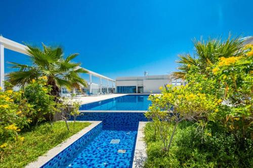 a swimming pool with a palm tree and a building at Contemporary Full Ocean View Apartment in Ras al Khaimah