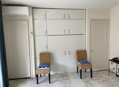 une chambre avec deux chaises et des armoires blanches dans l'établissement studio standing cannes croisette, à Cannes