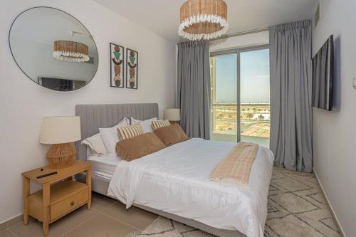 een slaapkamer met een bed en een groot raam bij Oceanfront Coastal Apartment in Ras al Khaimah