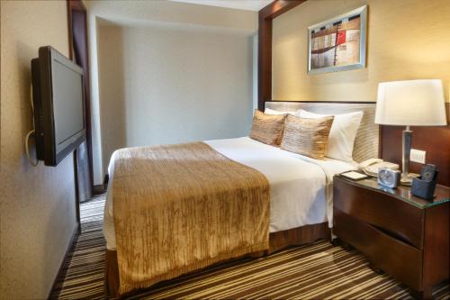 a hotel room with a bed and a flat screen tv at Leeden Hotel Guangzhou in Guangzhou