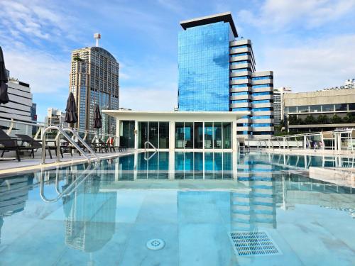 a pool in the middle of a city with tall buildings at The Bless Hotel and Residence in Bangkok