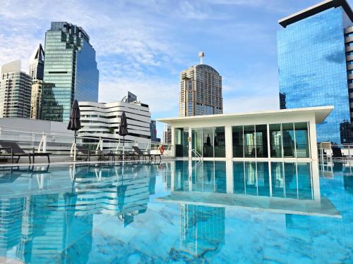 a hotel swimming pool with a city skyline in the background at The Bless Hotel and Residence in Bangkok