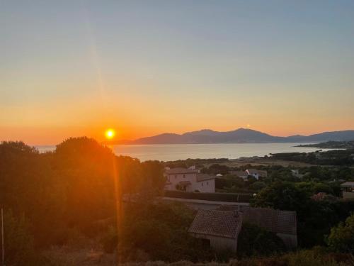 un coucher de soleil sur l'eau et une ville au soleil dans l'établissement Villa vue mer piscine, à Pietrosella
