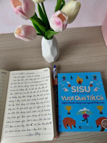 two books sitting on a table with a vase of flowers at Sophia Healing House Cần Thơ in Can Tho