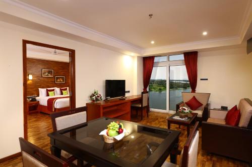 a living room with a room with a bed and a table at JVK Park Hotel in Cochin