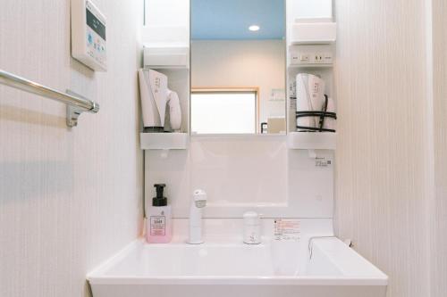a white bathroom with a sink and a mirror at 楓の宿 Osaka Midoribashi5min 5ppl liubj8 in Osaka