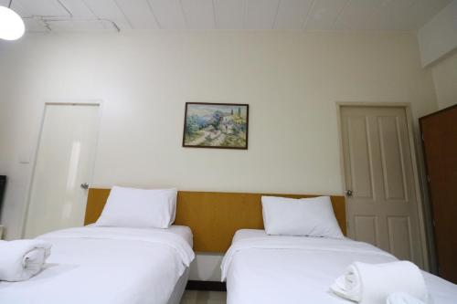 two beds in a room with a picture on the wall at JL Bangkok Hotel in Bangkok