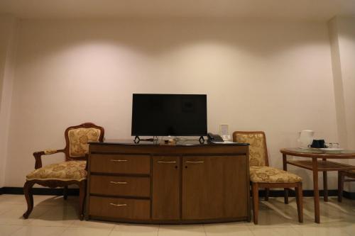 a living room with a tv and two chairs at JL Bangkok Hotel in Bangkok