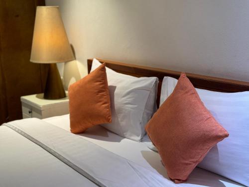 a bed with three pillows on it with a lamp at JL Bangkok Hotel in Bangkok