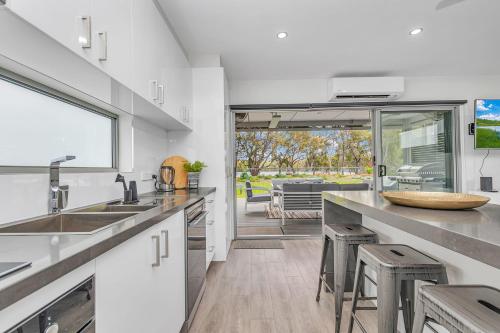 a kitchen with a sink and a counter with stools at 56@Highview-Echuca Holiday Homes in Moama
