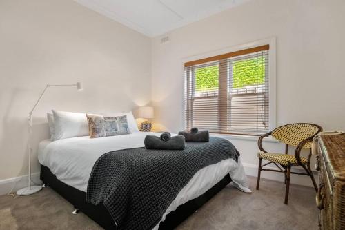 a bedroom with a bed and a chair and a window at Two Terrific Albert Park Apartments in Albert Park