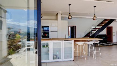 a kitchen with a island with bar stools and a staircase at La Villa Phoenix in Saint-Pierre