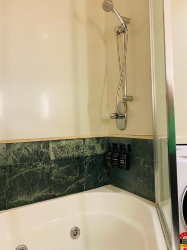 a white bath tub with a shower in a bathroom at Ocean View Studio Apartment Surfers Paradise - Free Parking in Gold Coast