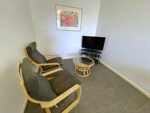 a living room with three chairs and a tv at Getaway Villas Unit 386 in Exmouth