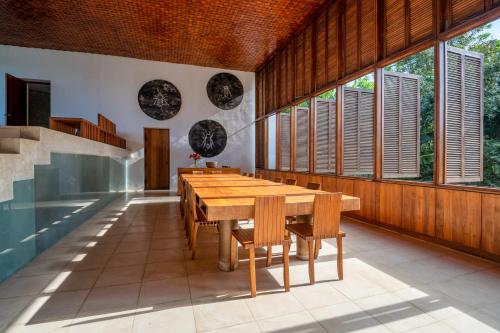 a dining room with a wooden table and windows at Villa Vista by The Serendipity Collection in Mirissa