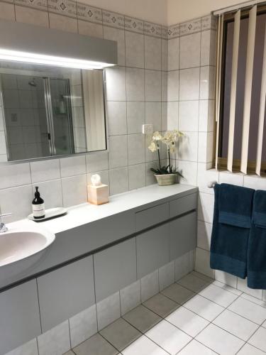 a bathroom with a sink and a mirror and blue towels at Marina Upstairs Apartment & Marina Downstairs Retreat Beresford in Geraldton