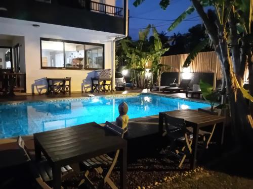 a child sitting next to a swimming pool at night at Villa Belza et SPA in Saint-Pierre