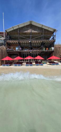 a building with tables and red umbrellas on the beach at Ecohotelhector in Playa Blanca