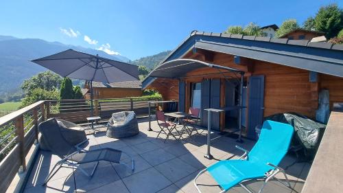 a deck with chairs and an umbrella and a cabin at Alt'O Martinets 28 in Nendaz