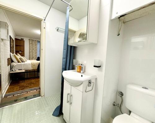 a bathroom with a sink and a toilet and a bedroom at Central Subiaco Oasis 1 Bedroom Unit in Perth