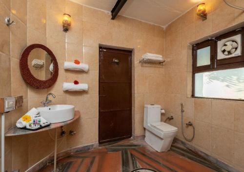 une salle de bain avec toilettes, lavabo et miroir dans l'établissement Arise Ethnic Village Resort - Manesar Bilaspur, à Gurgaon