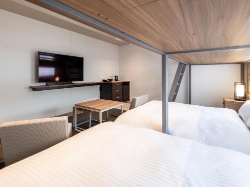 a bedroom with two beds and a tv on the wall at Nishitetsu Hotel Croom Hakata Gion Kushida Shrine in Fukuoka