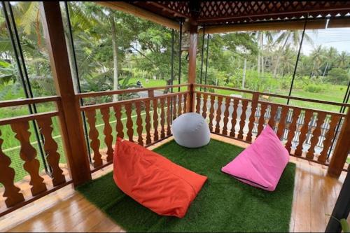 eine Veranda mit zwei farbigen Kissen auf einem Balkon in der Unterkunft Argo limo Cottage Syariah Magelang in Tanayung