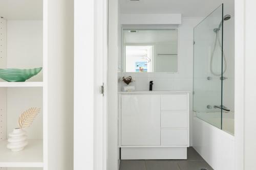 a white bathroom with a sink and a shower at Columbia Beachfront Apartments on Rainbow Bay in Gold Coast