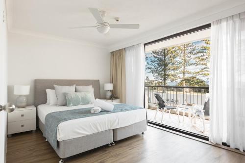 a white bedroom with a bed and a balcony at Columbia Beachfront Apartments on Rainbow Bay in Gold Coast
