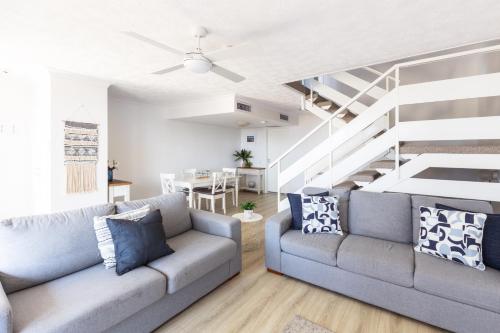 a living room with a couch and a staircase at Columbia Beachfront Apartments on Rainbow Bay in Gold Coast