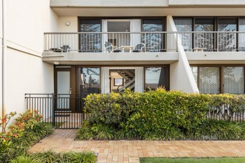 a house with a balcony and bushes at Columbia Beachfront Apartments on Rainbow Bay in Gold Coast
