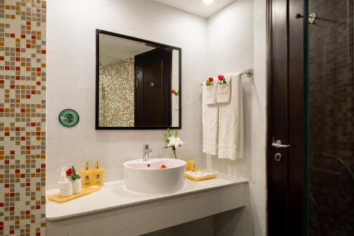 a white bathroom with a sink and a mirror at Sandals Lily Hotel in Da Lat
