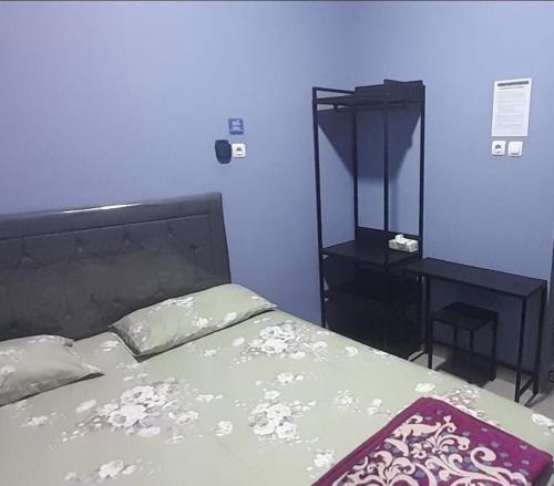 a bedroom with a bed and a blue wall at My Homestay SYARIAH in Sarongge