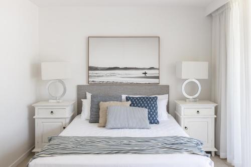 a white bedroom with a bed with two night stands at Columbia Beachfront Apartments on Rainbow Bay in Gold Coast